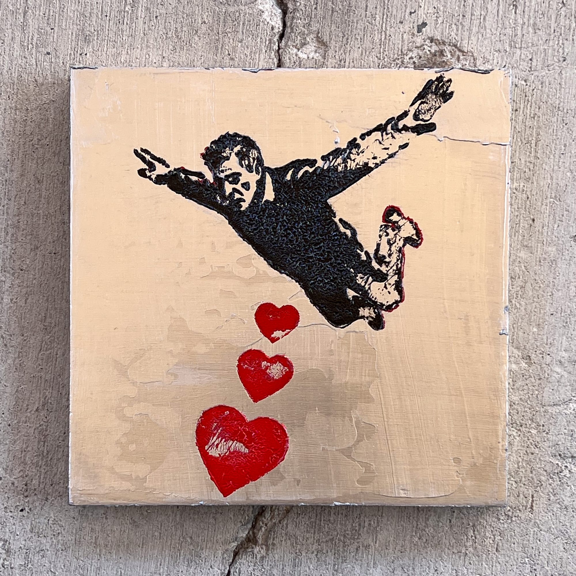 Silver painting with black figure in free fall and red hearts on a metallic ground, stark graphic contrast between elements.