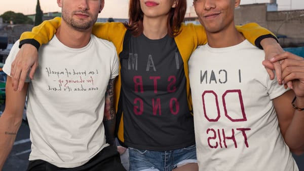 Three people wearing mirrored text tees: ‘I Am Strong,’ ‘I Can Do This,’ and handwritten ‘proud of myself for showing up’.
